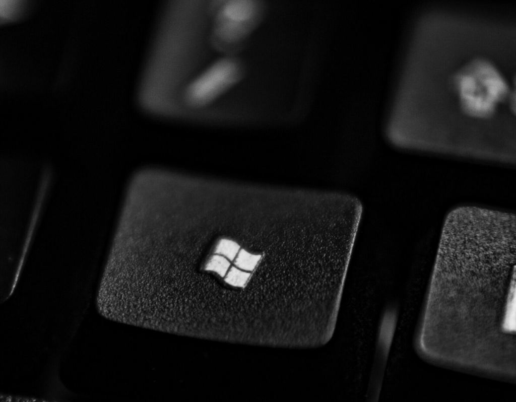 Zbliżenie czarnego klawisza klawiatury komputera wyświetlającego logo Windows w kolorze białym, z otaczającymi klawiszami rozmytymi w tle.